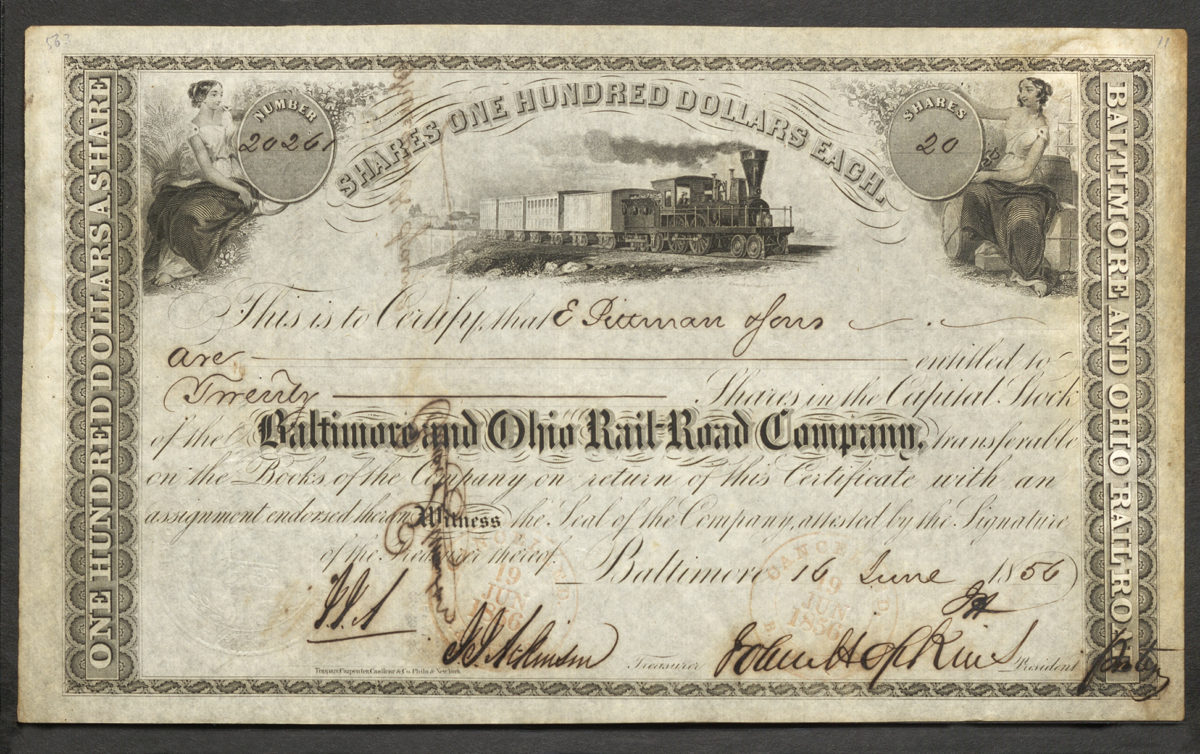 This stock certificate (No. 20261) represents 20 shares valued at $100 each for the Baltimore and Ohio Railroad Company. Two vignettes in the top corners each feature a woman dressed in a white dress with a blanket draped over her knees. The left woman is sitting on a bushel of wheat and is holding a hand scythe, and the right woman is sitting on several barrels and boxes holding a rapier-looking rod. The center vignette depicts a train with five cars linked and a bridge and several buildings behind it. This certificate also shows the company’s corporate seal and two stamps denoting cancellation (see Translation field for more).