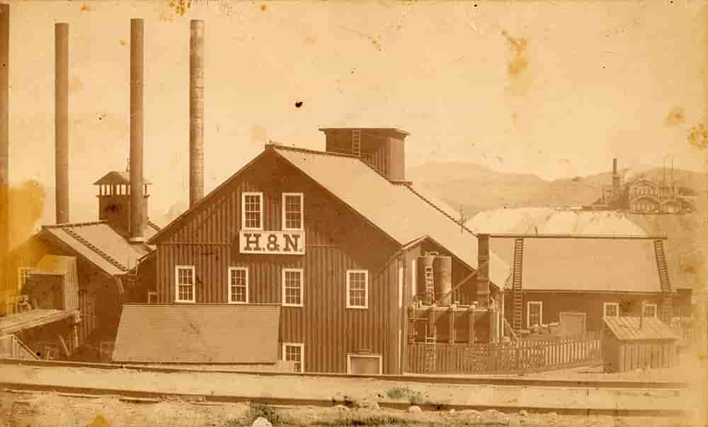 A sepia-toned photograph of the main building of the mine with smoke stacks.